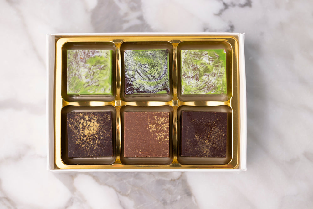 Box of chocolates with green and brown patterns on a marble surface