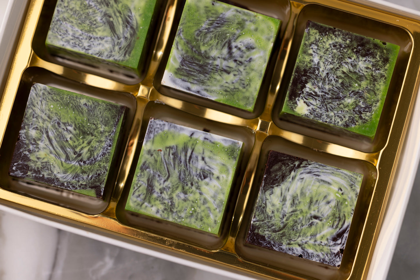 Green and black swirled confections in a gold box