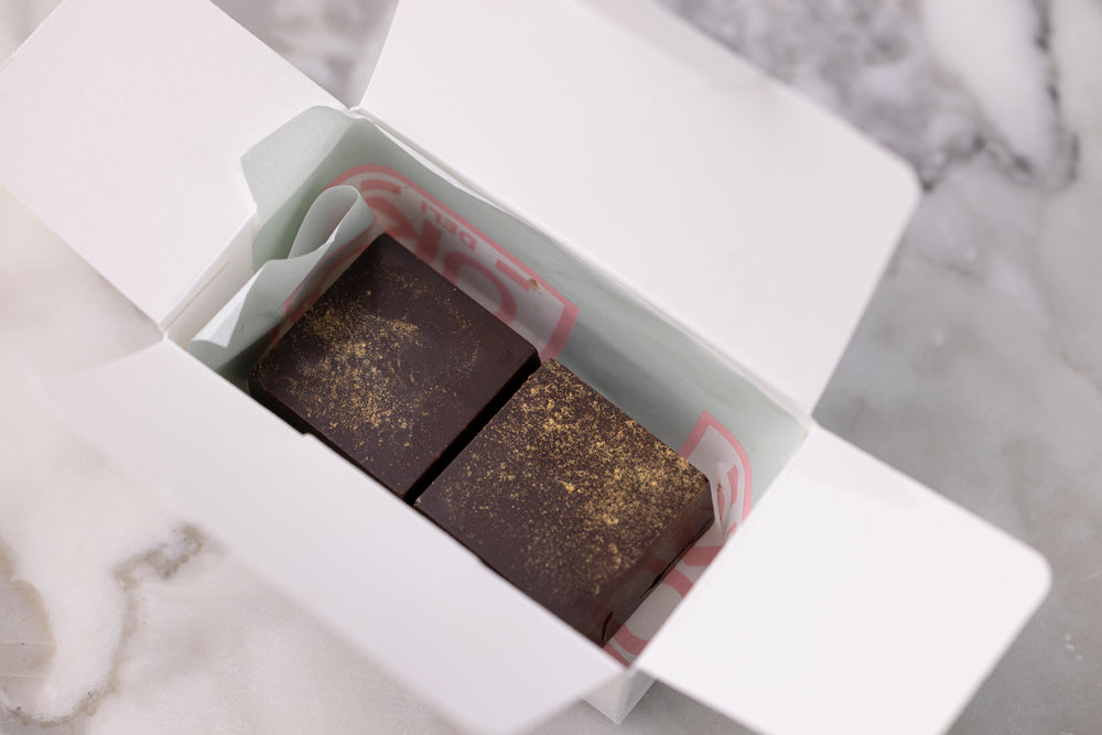 Two dark chocolate bars in a white box on a marble surface